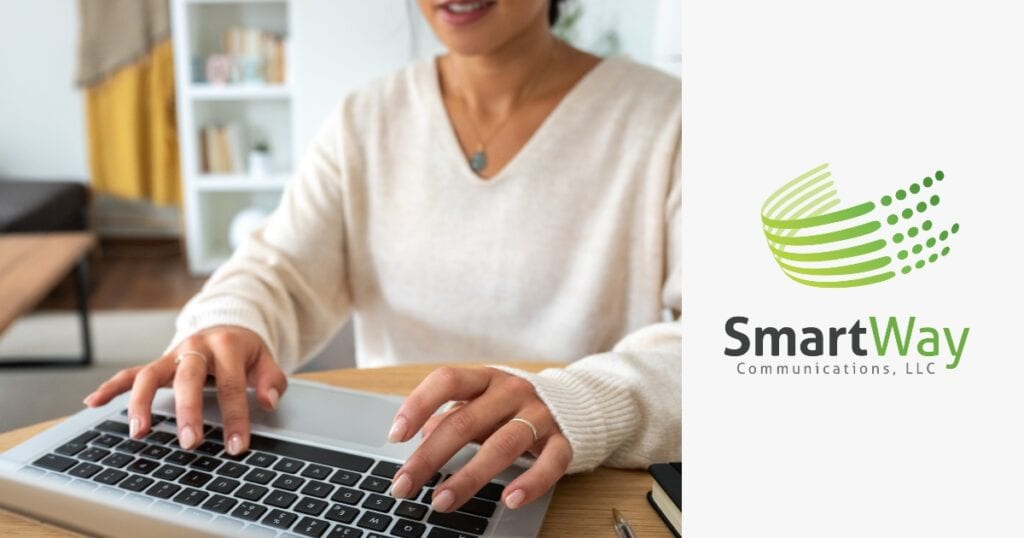A woman in a white sweater is typing on a laptop.