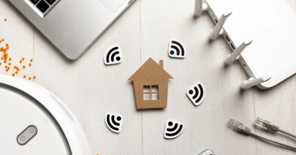 Image with computer, router, wireless cables, cardboard cut out house and wifi signal symbols